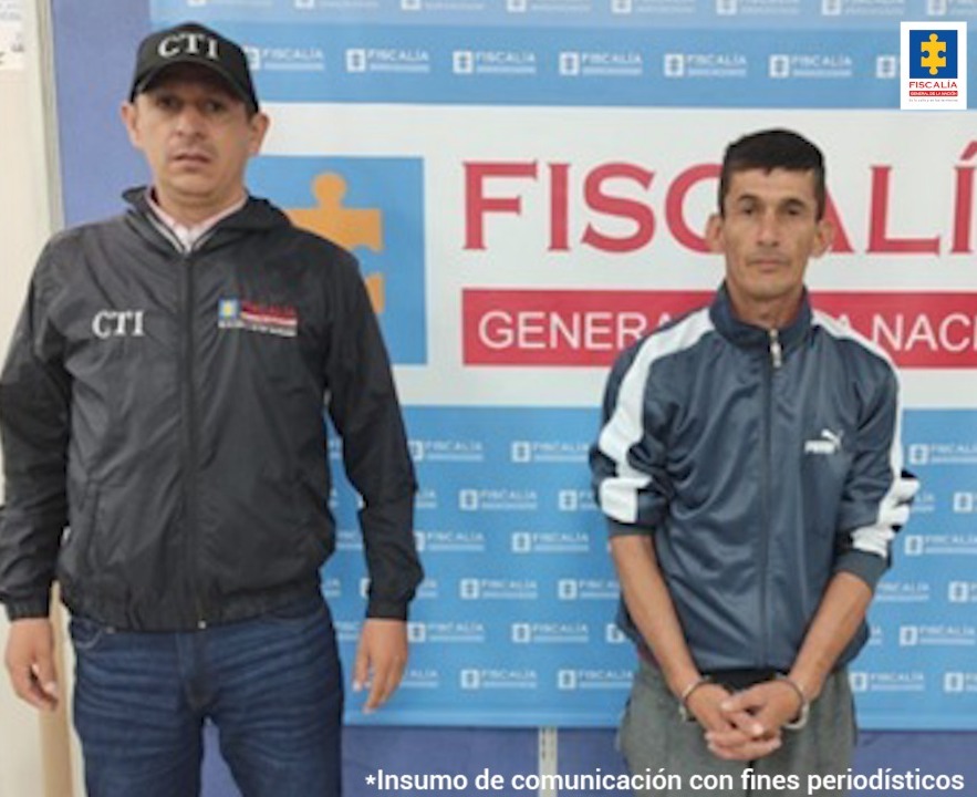 En la imagen se ve una persona detenida custodiado por un investigador del CTI. Detrás suyo un backing de la Fiscalía.