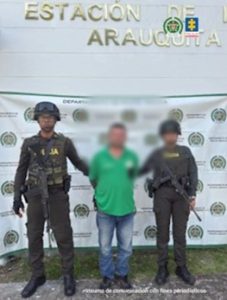 Se visualiza al capturado junto a dos uniformados de la Policía Nacional. Detrás de ellos el banner que identifica a la Policía Nacional.