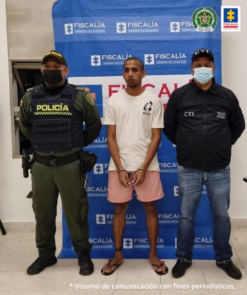 En la fotografía aparece un hombre capturado, junto a personal de la Policía Nacional y del CTI. En la parte posterior de la imagen se ve un banner de la Fiscalía General de la Nación. 