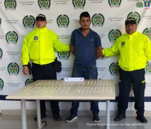 En la fotografía se aprecia de pie y los brazos atrás a Carlos Felipe Correa Sánchez. Viste camisa de manga corta color azul y jean azul. A los extremos de él hay uniformados de la Policía Nacional. Frente a ellos hay una mesa y sobre ella varias bolsas plásticas con contenido de color beage. Detrás del capturado y los uniformados hay un pendón institucional de la Policía.