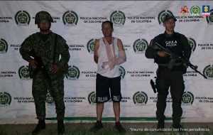 En la fotografía se aprecia de pie, un brazo atrás y otro adelante con cabestrillo a Carlos Julio Lizarazo Sepúlveda, alias Lizarazo. Viste camiseta esqueleto blanca, bermudas negras con la palabra ‘RUN’ en el borde de cada manga; así como zapatos negros. Al extremo izquierdo de él hay un uniformado de la Policía y al extremo derecho un uniformado del Ejército. Detrás de ellos hay un pendón institucional de la Policía.