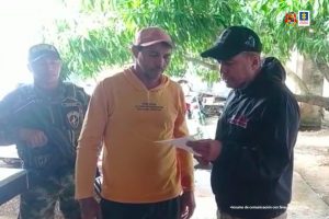 Un investigador del CTI lee los derechos del capturado y le informa el delito por el cual será judicializado. Lo custodia un uniformado de la Policía Nacional. La captura se realizó en una vereda de Planeta Rica (Córdoba).