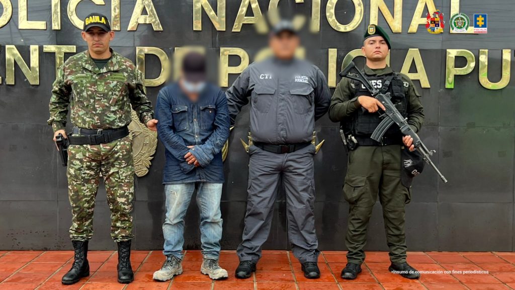 En la foto aparece el capturado custodiado un servidor del Cuerpo Técnico de Investigación CTI y un uniformado del Gaula Militar y de la Policía Nacional. En la foto también aparece de fondo un backing de la Policía Nacional.