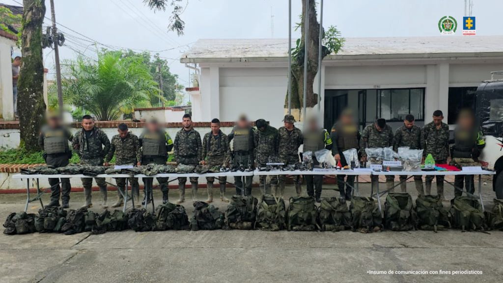 Los capturados se encuentran de frente y custodiados por uniformados de la Policía Nacional. En la foto se observa una mesa con el material incautado.