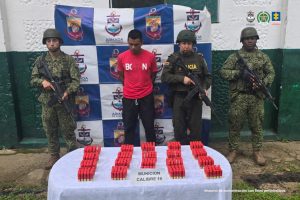 En la foto aparece el capturado custodiado por dos uniformados de la Armada Nacional. En la foto también aparece un backing de la Armada y la munición incautada.