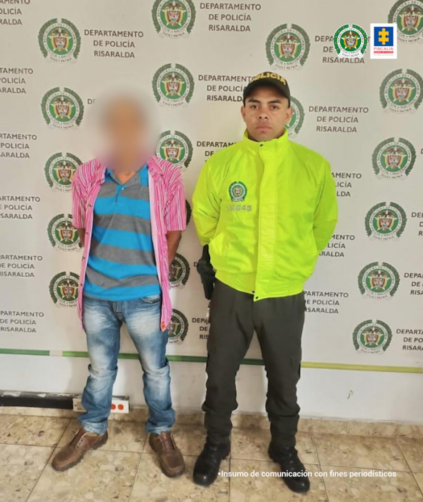 En la segunda fotografía se observa a un capturado, masculino, y a un costado, funcionario de Policía Nacional. Atrás pendón de Policía Nacional