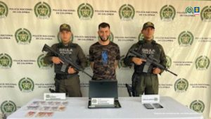 En la foto aparece el capturado custodiado por dos uniformados del Gaula de Policía Nacional. En la foto también aparece un backing de la Policía Nacional, el computador, celulares y dinero en efectivo.