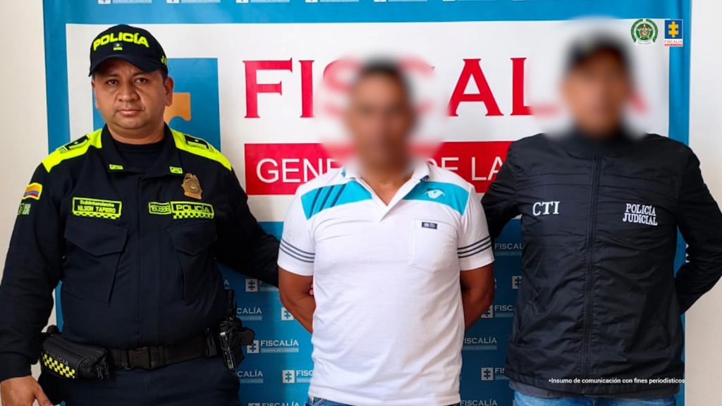 En la foto aparece el capturado custodiado por un servidor del Cuerpo Técnico de Investigación y de la Policía Nacional.  En la foto también aparece de fondo un backing de la Fiscalía General de la Nación.