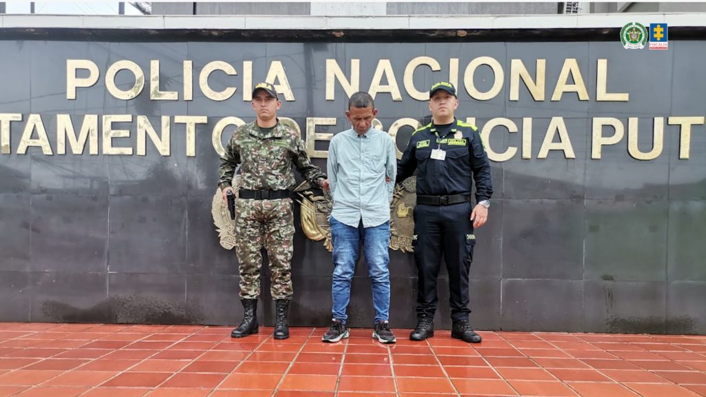 En la foto aparece el sentenciado custodiado por un uniformado del Gaula del Ejército y también un uniformado de la Policía Nacional. En la foto también aparece de fondo un mural de la Policía Nacional.