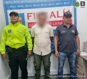  El procesado se encuentra esposado y en custodia por uniformado del Cuerpo Técnico de investigación y la Policía Nacional. Detrás suyo un backing de la Fiscalía. 