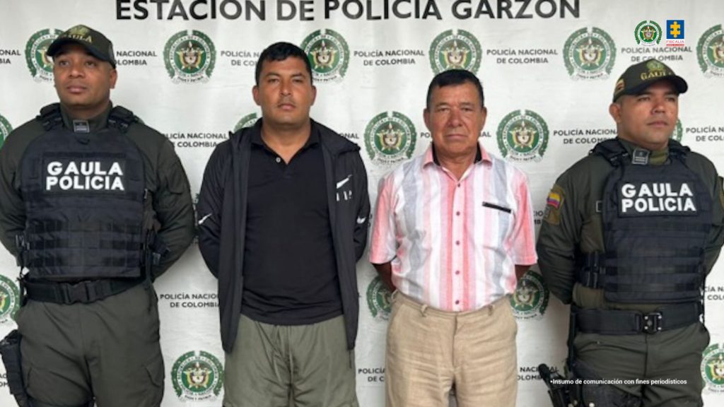 En la foto se observan a dos de los capturados, custodiados por dos uniformados del Gaula de la Policía Nacional. También se observa un backing de la Policía Nacional.