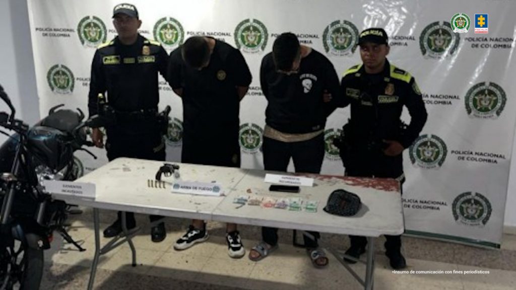 En la foto aparecen los capturados custodiados por dos uniformados de la Policía Nacional.  En la foto también aparece de fondo un backing de la Policía Nacional y los elementos que les habían hurtado a las víctimas.