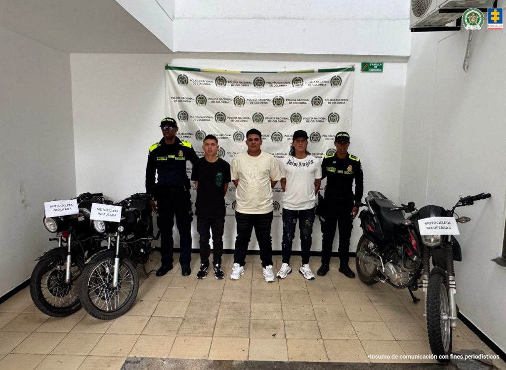 En la foto aparecen los capturados de frente y custodiados por dos uniformados de la Policía Nacional. De fondo aparece un backing de la Policía Nacional y las motos incautadas.