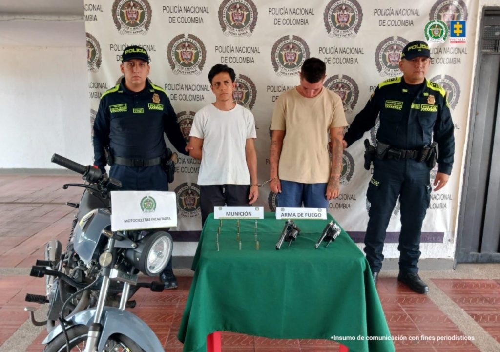 En la fotografía se observan cuatro personas, dos de ellas los capturados acompañados de dos uniformados de la Polcía Nacional.