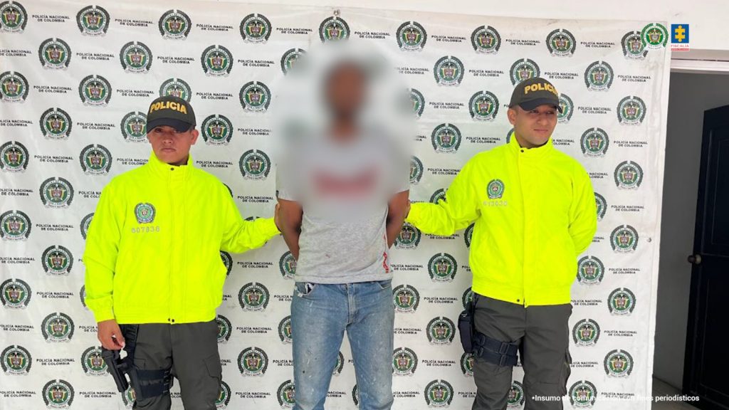 En la foto se observa al capturado custodiado por uniformados de la Policía Nacional. También se observa un backing de la Policía Nacional.