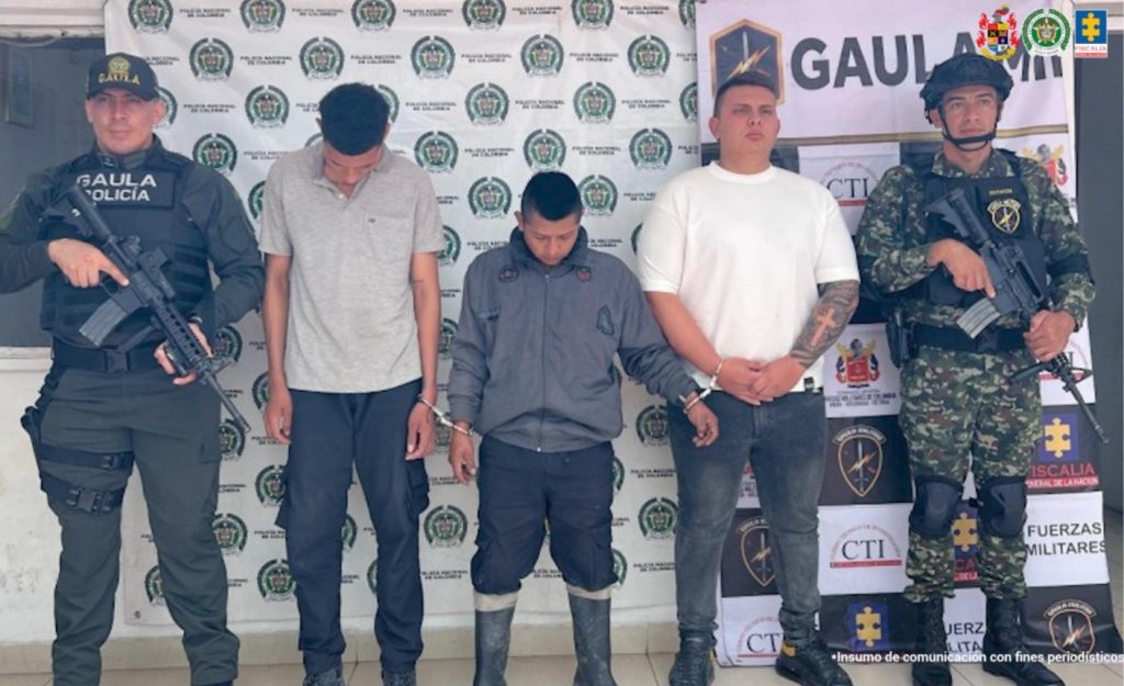 En la foto se observa a los tres capturados custodiados dos uniformados de la Policía y Ejército Nacional. Detrás se observa un backing de la Policía Nacional.