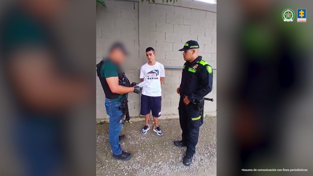 En la fotografía se aprecia de pie y con los brazos atrás a César Andrés Manrique Isidro. Viste camiseta de color blanco, manga corta; bermuda negra y zapatillas blancas con negro. A su derecha hay un servidor del CTI de la Fiscalía y a su izquierda un uniformado de la Policía Nacional.