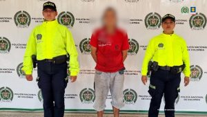 En la imagen se ve al capturado con buzo color rojo, una bermuda de jean en custodia por dos uniformados de la Policía Nacional.