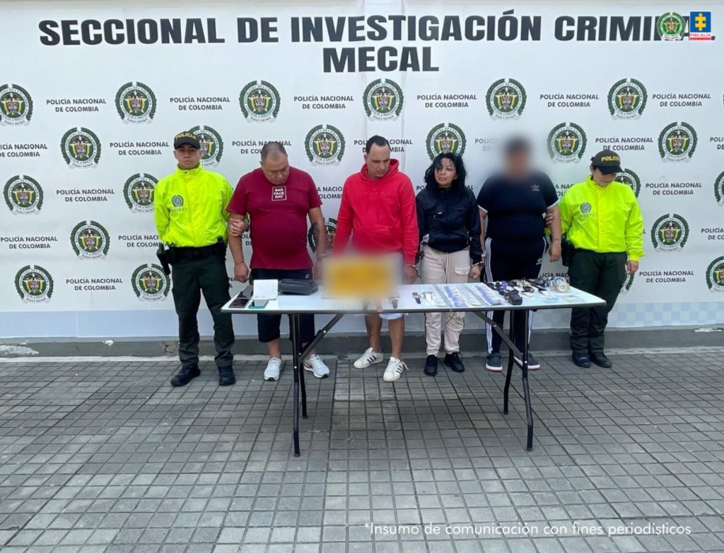 En la fotografía aparecen de pie y esposados entre sí a los presuntos implicados en hurtos a residencias. Entre ellos hay una mujer. A sus extremos hay uniformados de la Policía Nacional. Delante de ellos hay una mesa y sobre ella se aprecian elementos como celulares, relojes, dinero en efectivo, entre otros. Detrás de ellos hay un pendón institucional de la Policía.