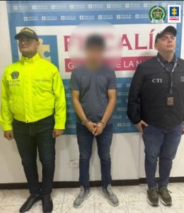 capturado esposado de frente custodiado por investigador del CTI de la Fiscalía y policía. Detrás banner de la Fiscalía.