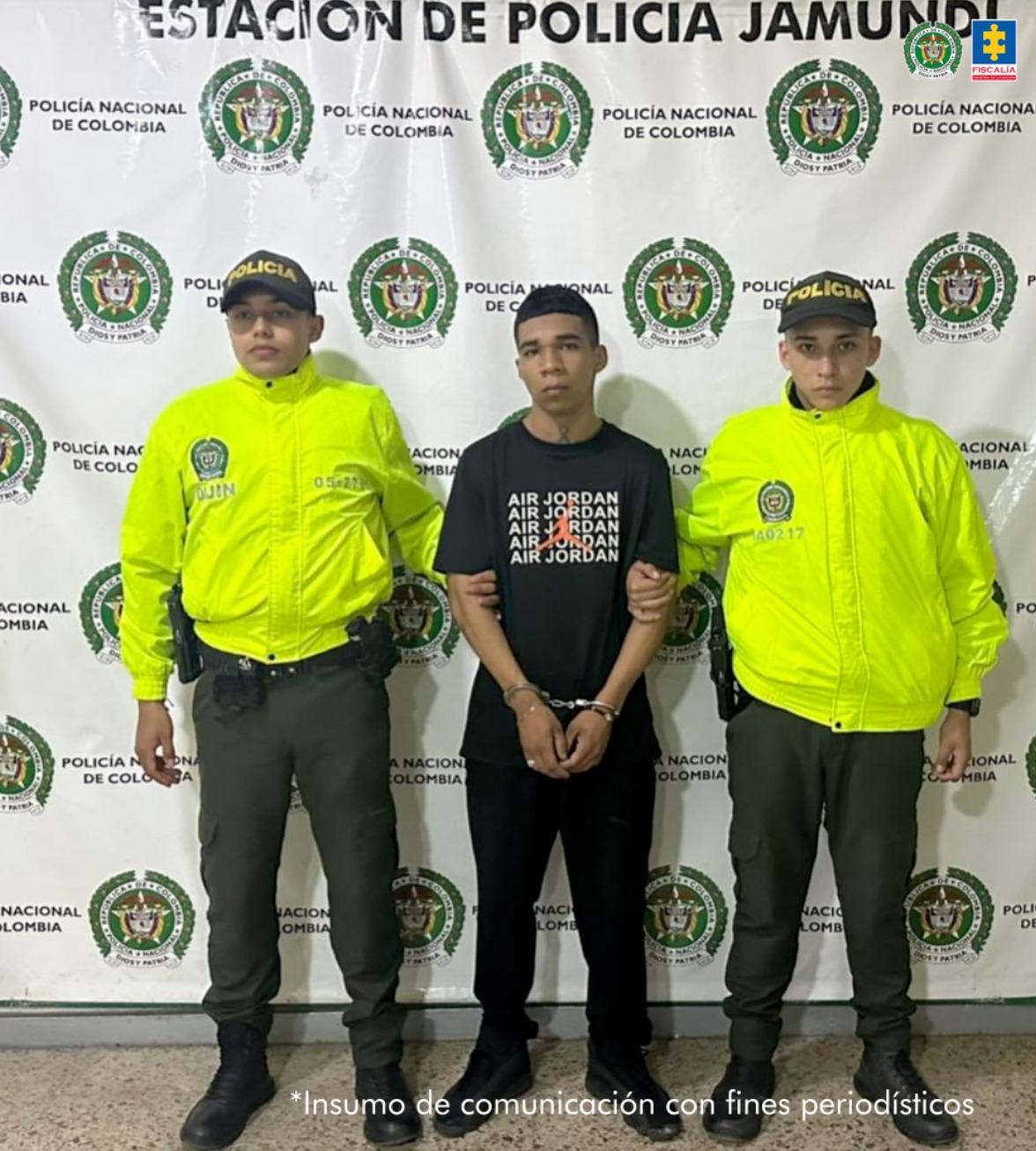 En la fotografía se aprecia de pie, con los brazos adelante y esposado a Cristian Camilo Conde Tintinago, alias Ambiti. Viste camiseta de color negro, manga corta, las palabras ‘Air Jordan’ estampadas en color blanco a la altura de pecho; así como la siluet de un hombre saltando en color naranja. A sus extremos hay uniformados de la Policía Nacional y detrás de ellos hay un pendón institucional de la Policía.
