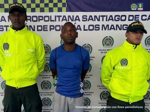 En la fotografía se aprecia de pie y con los brazos atrás a Cristhian Iván Angulo Vélez. Viste camiseta de manga corta color azul con rayas blancas; pantalón gris. A los extremos de él hay uniformados de la Policía Nacional. Delante de ellos hay una superficie verde y sobre ella hay un letrero, con logos de la Policía, que dice: ‘Captura por orden judicial’. Detrás de ellos hay un pendón institucional de la Policía.