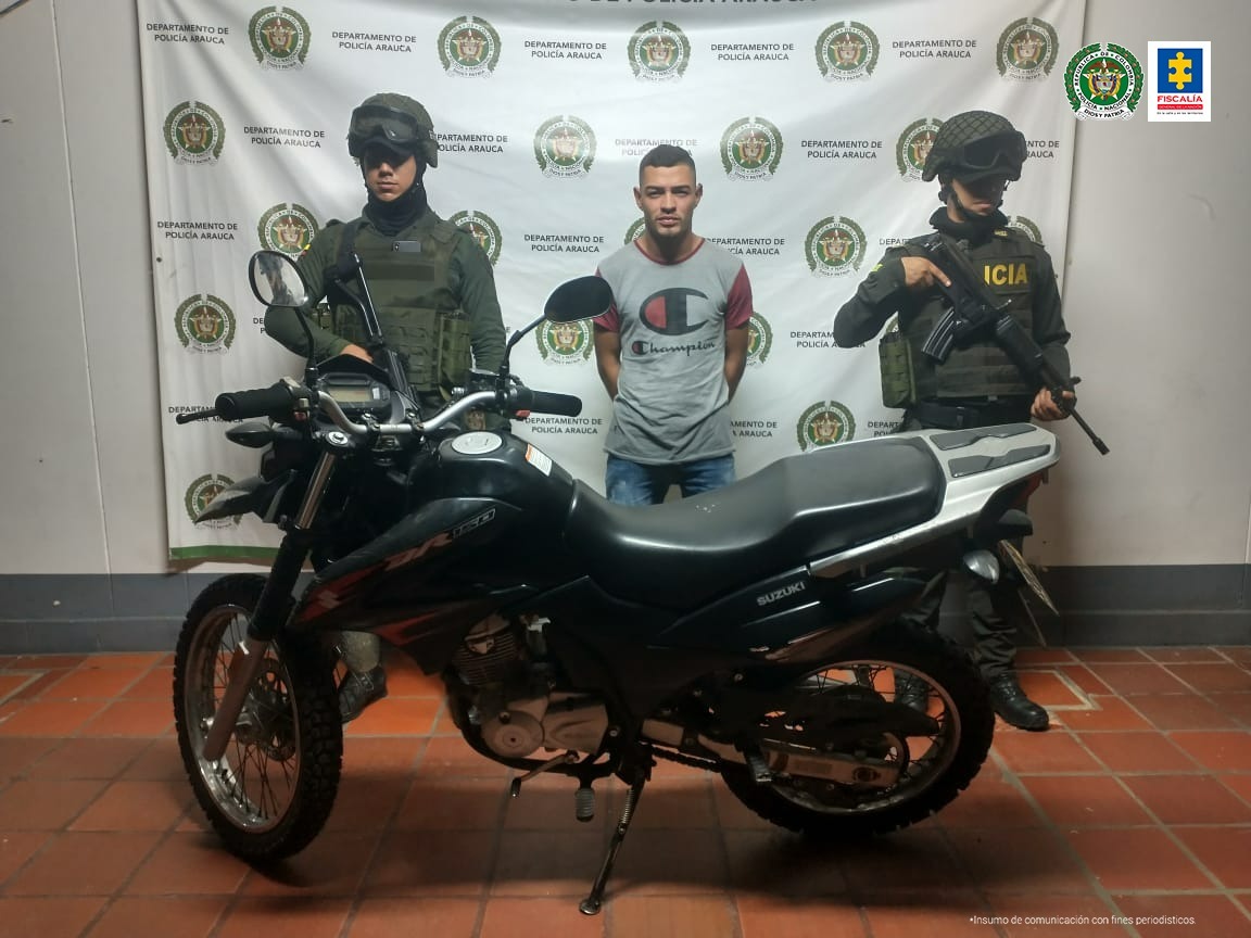 En la fotografía se aprecia el capturado entre dos uniformados de la Policía Nacional, al frente la motocicleta recuperada. En la parte posterior se observa el banner de la Policía Nacional.