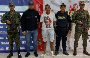 En la fotografía se aprecia de pie y con los brazos atrás, a Cristopher Rivera Olivar. Viste camiseta de manga corta blanca, con estampado de colores ; bermuda de jean azul claro y desgastado; así como zapatillas blancas. Al lado derecho de él hay un servidor del CTI de la Fiscalía y un uniformado del Ejército. Al lado izquierdo hay un uniformado de la Policía y otro del Ejército. Detrás de ellos hay dos pendones institucionales: uno, de la Fiscalía y otro del Ejército Nacional.