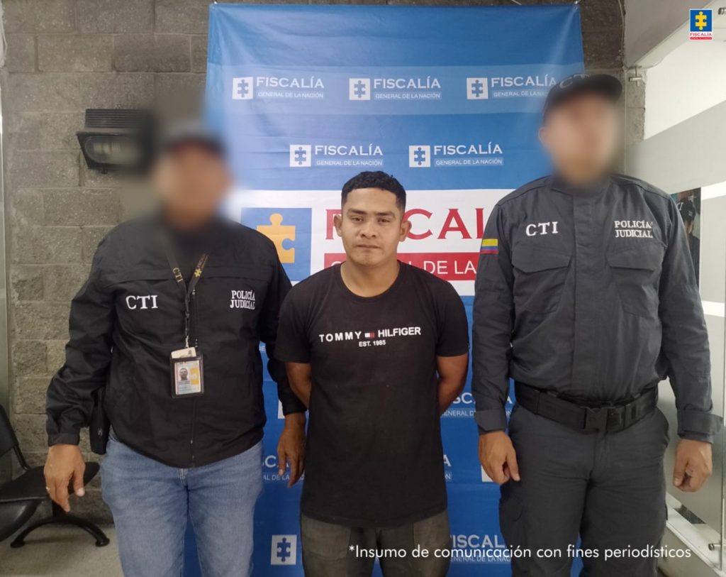 En la imagen aparece una persona de suéter negro entre dos uniformados del CTI.