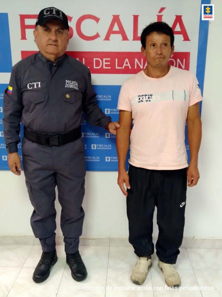 En la fotografía aparecen tres capturados, junto a personal de Policía Nacional y Fiscalía General de la Nación. En la parte posterior de la imagen se ven banners de Policía Nacional y la Fiscalía General de la Nación.