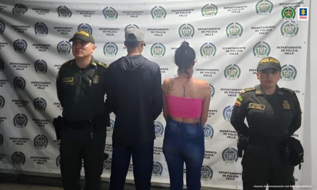 En la foto aparecen de pie y de espaldas a la cámara Daniela Loaiza Llanos y José Andrés Martínez Barón. El hombre viste buzo y pantalón oscuros, y gorra. La mujer tiene el cabello recogido en una cebollita, blusa rosada extraple y jean azul. A lado y lado de ellos hay uniformados de la Policía Nacional. En la parte posterior hay un pendón institucional de la Policía.