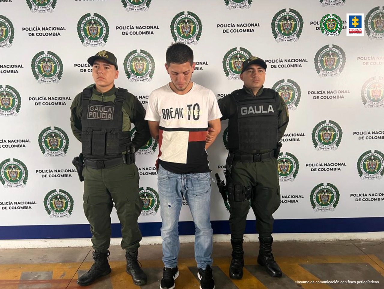 En la foto se ve al capturado de frente y en cada costado un funcionario del Gaula de la Policía Nacional. Al fondo un pendón de Policía Nacional