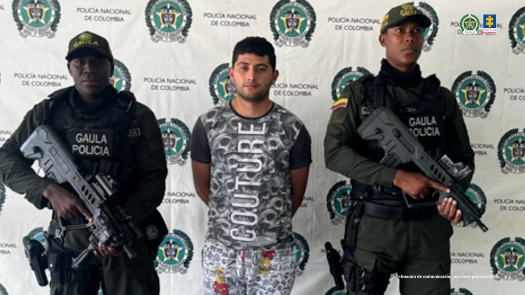 En la fotografía se aprecia de pie y con los brazos atrás a Dayron Esteban Candamil Mendieta, alias Mendieta o Andrés. Viste camisa con estampado tipo camuflado gris con blanco y mangas cortas de color negro; pantalón estampado con gris y blanco, con imágenes de un personaje de dibujos animados de color amarillo con rojo; así como zapatillas negras. En sus extremos hay uniformados de la Policía Nacional. Detrás de ellos hay un pendón institucional de la Policía.