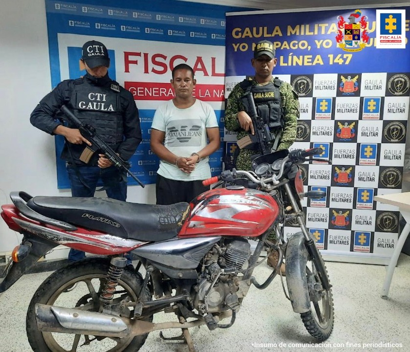 En la imagen se ve un hombre capturado entre dos funcionarios del CTI y el Gaula Militar y frente a una motocicleta incautada.