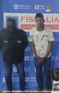 En la imagen aparece una persona con camisa de flores y jean, junto a un investigador del CTI.