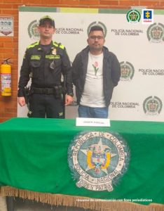 En la fotografía aparecen capturados junto a personal de Fiscalía y Policía Nacional. En la parte posterior de la imagen se ven banners de Policía Nacional y la Fiscalía General de la Nación.