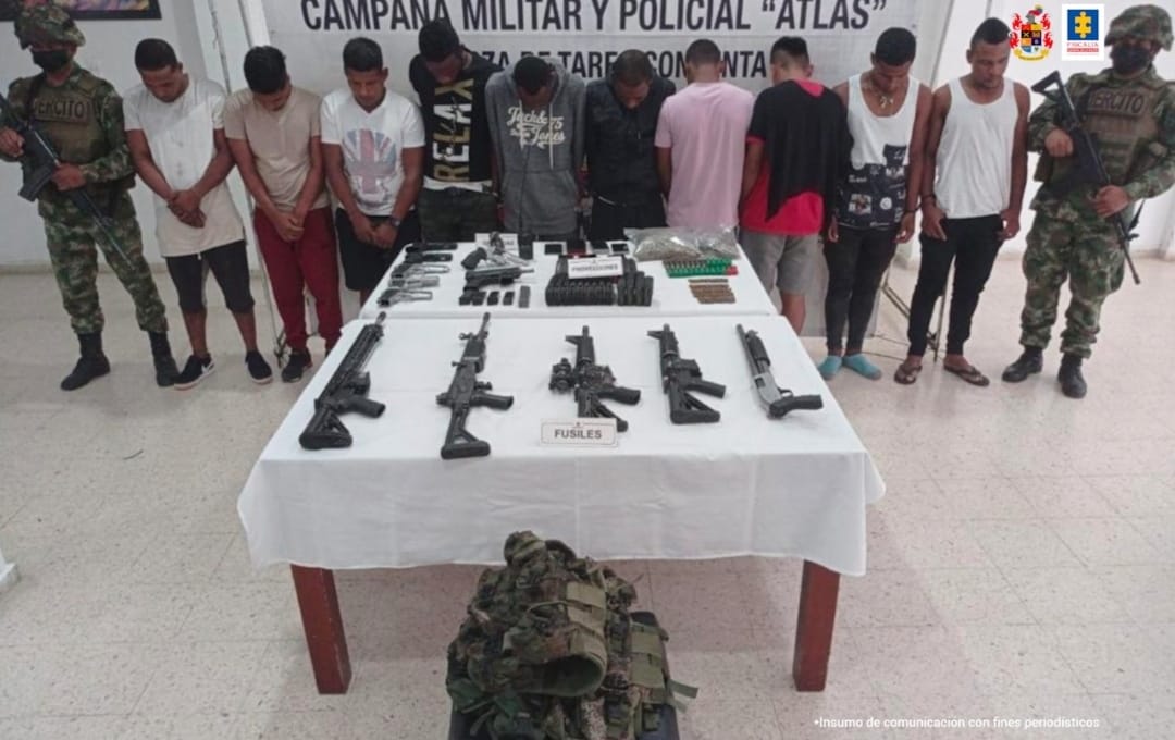 En la fotografía se observan a los 10 capturados junto a dos soldados del Ejército Nacional. En la parte posterior se observa una mesa con armas de fuego, proveedores, munición y un morral