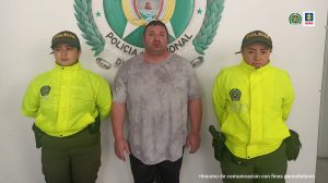 En la fotografía aparece el ciudadano norteamericano con dos servidoras de la Policía Nacional a los lados