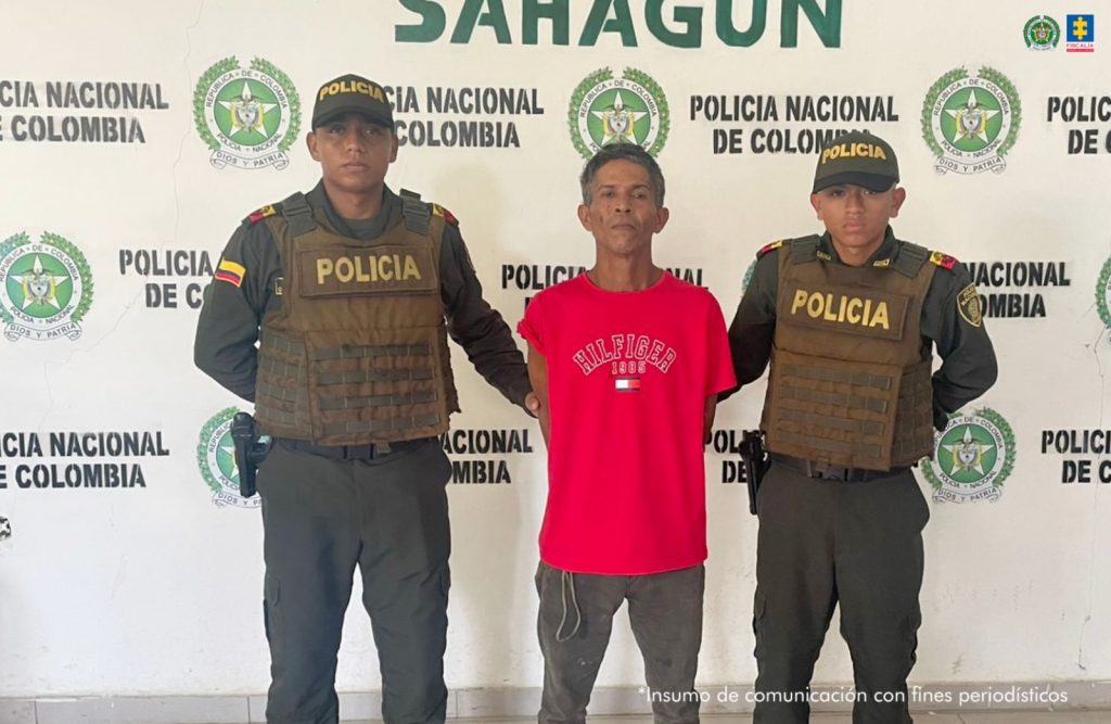 En la imagen aparece una persona de suéter rojo entre dos uniformados de la Policía Nacional.