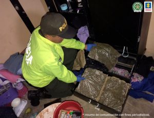 Está un policìa recogiendo droga incautada en una vivienda allanada.