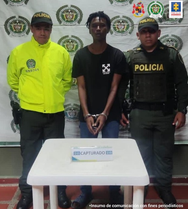 Edgar Andrés Hernández Palacios aparece en la foto con dos policías y un backing con logos de la Policia Nacional en la parte de atrás. Adelante una mesa blanca con un letrero que dice capturado.