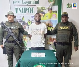 En la fotografía aparece el capturado junto a dos agentes de la Policía Nacional. En la parte superior se observa un banner de la Policía Nacional