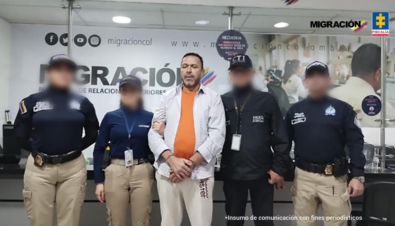 En la imagen, tomada el día de la captura, está el condenado con un servidor del CTI, una de Migración y 2 de la Interpol. Al fondo hay un pendón de Migración Colombia.