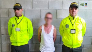 n la fotografía se aprecia de pie, con los brazos atrás y la cabeza agachada a David Esteban Montes González. Viste camisa de manga corta de color blanco, y pantalón azul. A sus extremos hay uniformados de la Policía Nacional. Detrás de ellos hay un pendón institucional de la Policía.
