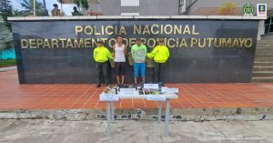 En la fotografía aparecen dos capturados, junto a personal de Policía Nacional. En la parte posterior de la imagen se ven banners de Policía Nacional y la Fiscalía General de la Nación.