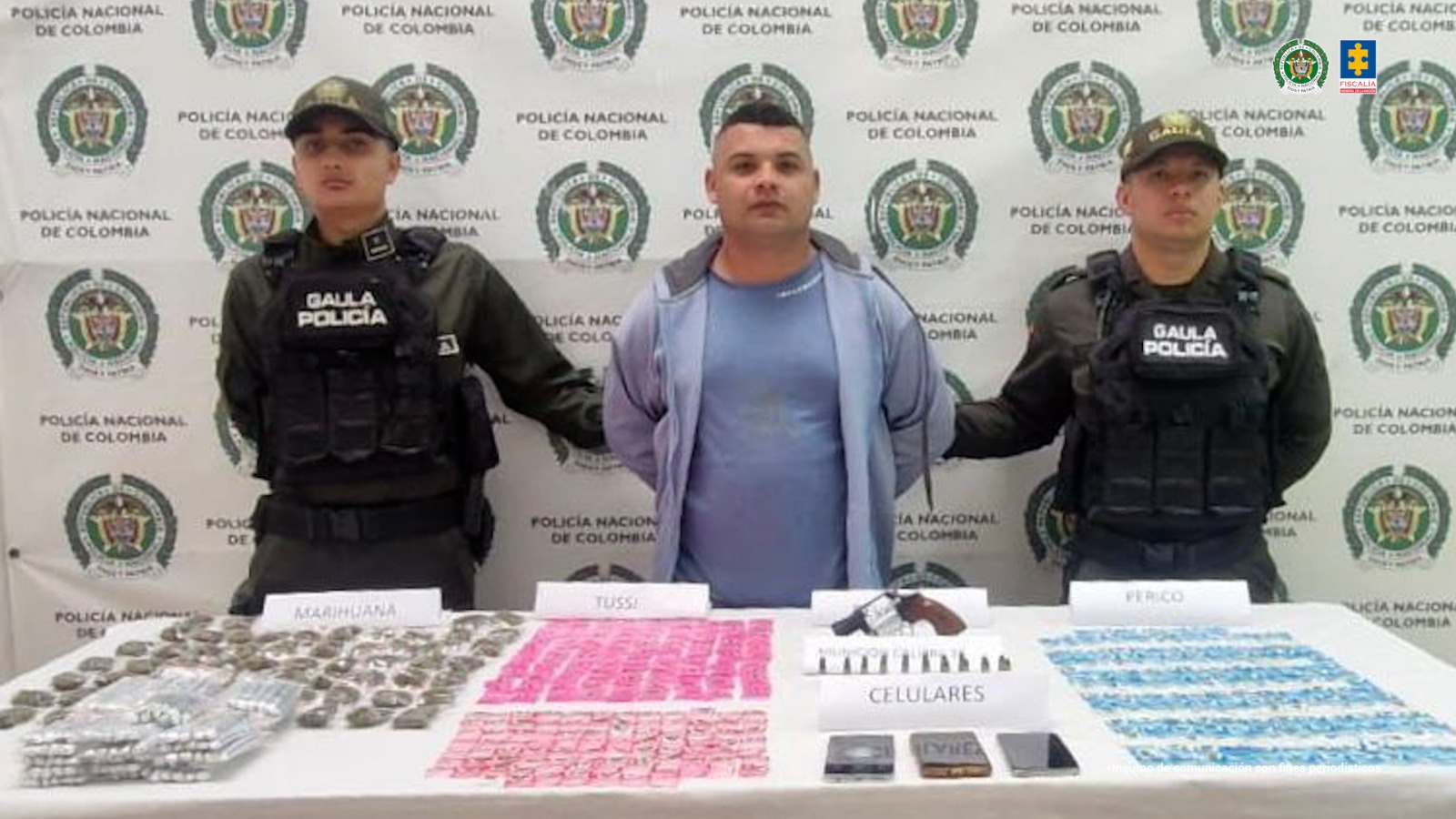 En la foto está el procesado en medio de 2 servidores del Gaula de la Policía, y una mesa con el estupefaciente y armas incautadas