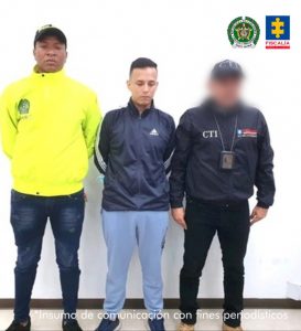 en la imagen se ve una persona detenida bajo custodia de un investigador del CTI y un miembro de la Policía Nacional.