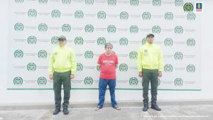 en la imagen se ve una persona detenida bajo custodia de dos policías.