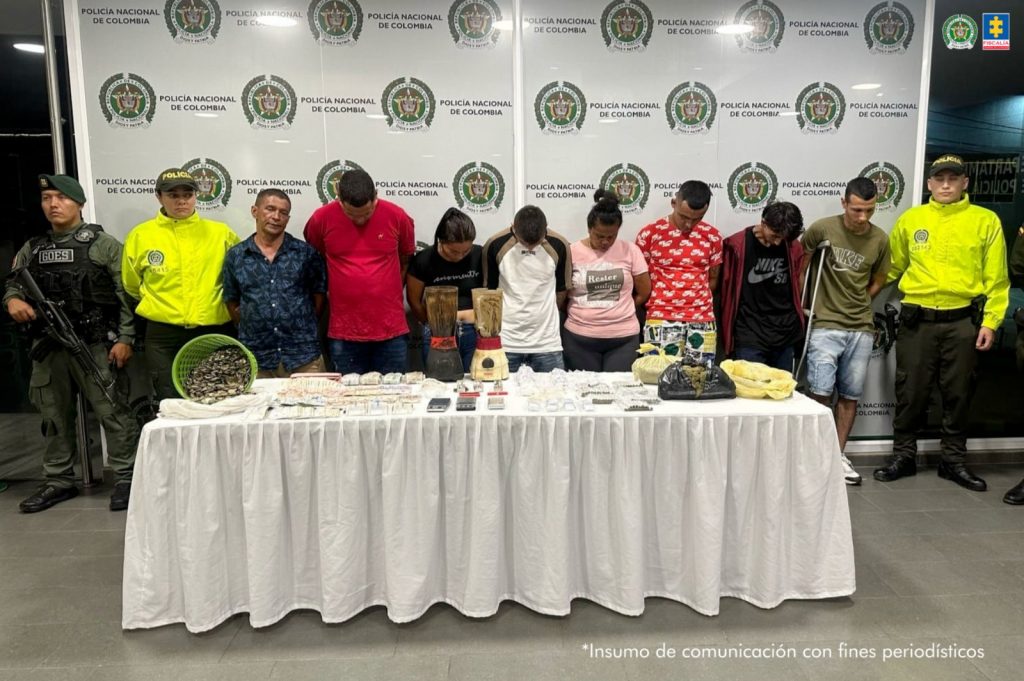 En la foto se observa a los capturados custodiados por uniformados de la Policía Nacional. También se observa un backing de la Policía Nacional y el material incautado como sustancias alucinógenas, y dinero en efectivo.