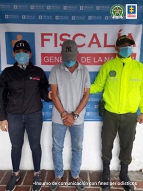 En la fotografía aparece el capturado junto a un investigadora del CTI y un uniformado de la Policía Nacional. En la parte posterior su observa el banner que identifica a la Policía Nacional.